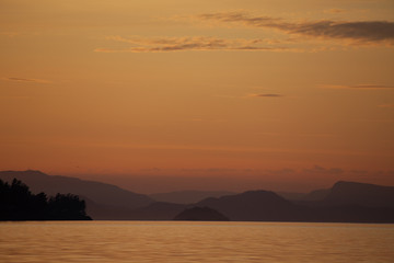 Landscape sunset pink hues over the mountains, islands, and water of the Pacific Northwest