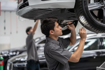 Asian mechanic Checking and torch tire in maintainance service center which is a part of showroom, technician or professional work for customer concept