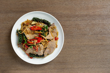 top view of stir fried sizzle pork in a ceramic dish on wooden table. asian homemade style food concept.