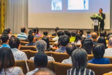 Obraz premium Back side of audience listening the Speaker with podium on the stage in the conference hall, business and education concept