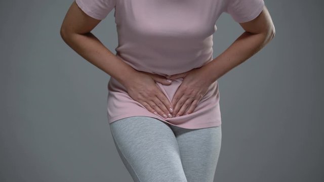 Woman writhing from pain in lower abdomen, menstrual pain, risk of miscarriage