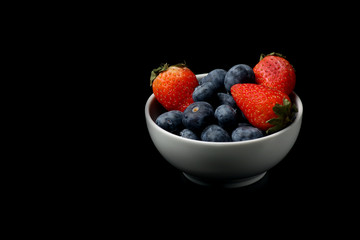 a bowl of strawberry and blueberry isolated on black background