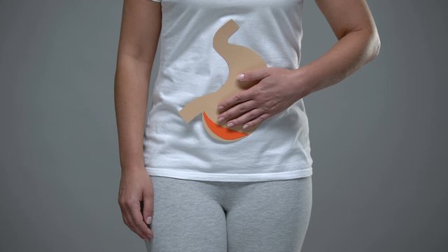 Woman holding paper stomach sign, gastritis prevention, gastrointestinal tract