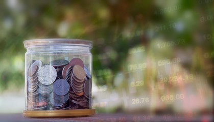 Business concept:  many coins in the glass with blurred picture of stock graph background.
