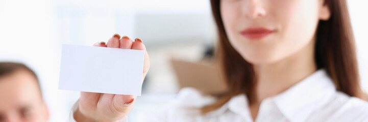 Female hand in suit give blank calling card to visitor closeup. White collar partners company name exchange executive or ceo introducing at conference product consultant sale clerk concept