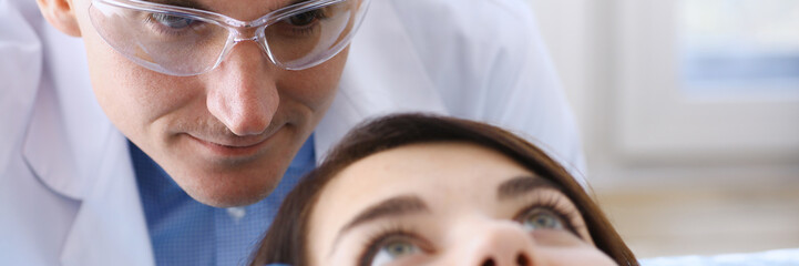 A woman at the reception of a male dentist examining teeth and oral cavity