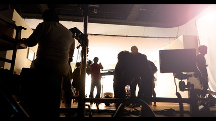 Silhoutte images of video production and lighting set for filming which movie crew team working and...