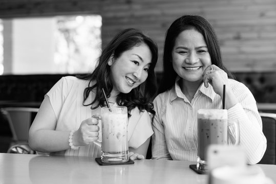 Two Mature Asian Women Together Hanging Out At The Coffee Shop While Having Fun