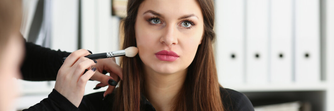 Beautiful brunette businesswoman hold in arm phone at workplace portrait wile getting makeup preparing for tv air. Negotiate meeting job busy life style device store concept
