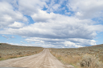 Winding dirt road among the hills with desert like landscape, grasslands and bush in Kamloops, British Columbia. Lac Du Bois