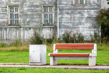 bench and litter bin with old shabby house on the background