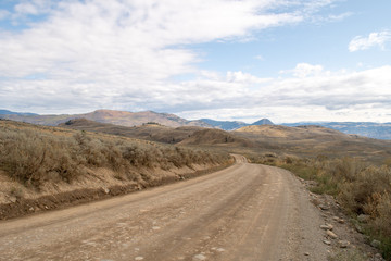 Dirt winding road in the mountains in the rural pasture lands on the hills in Lac Du Bois Grasslands protected area, Kamloops