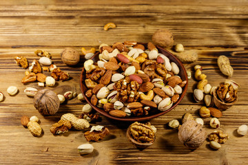 Obraz na płótnie Canvas Mixed nuts on wooden table. Walnuts, pistachio, almond, peanut, cashew, hazelnut in ceramic bowl. Healthy eating concept