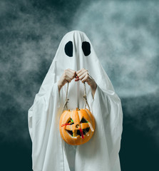 Halloween white ghost holding pumpkin basket with candies.
