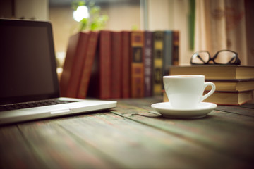 A cup of coffee in the workplace on a wooden table.