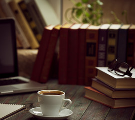 A cup of coffee in the workplace on a wooden table.