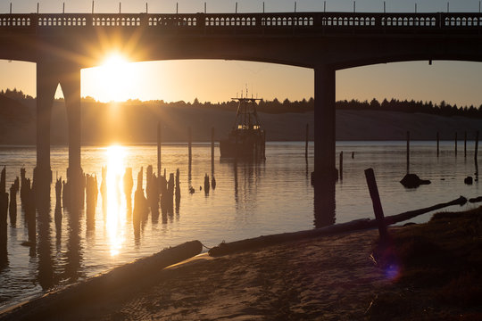 Evening light on the Siuslaw River and bridge, with a fishing boat on the water in Florence, Oregon.
