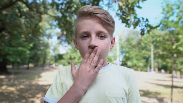 Shocked caucasian boy feeling overwhelmed standing in park, emotions concept