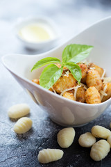 Closeup of italian potato gnocchi with sun dried tomatoes pesto served in a white bowl, vertical shot