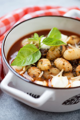 Close-up of potato gnocchi with tomato sauce, spinach, mozzarella and parmesan in a serving pan, vertical shot