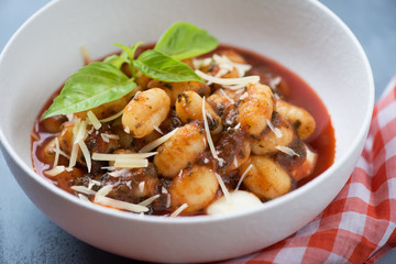 Close-up of potato gnocchi with tomato sauce, spinach, mozzarella and parmesan, selective focus
