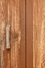 Old dirty brown painted wood background. Part of the door with a handle.