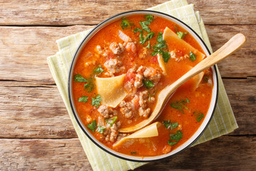 Portion of rich lasagna soup close-up in a plate. Horizontal top view from above