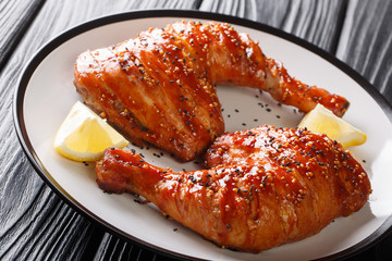 Grilled chicken quarter legs in honey-tomato marinade served with lemon closeup on a plate. horizontal