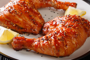 Glazed chicken leg quarters with sesame seeds and lemon close-up. horizontal