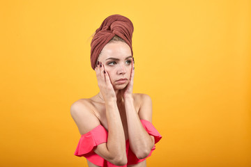 young girl with towel on her head over isolated orange background shows emotions