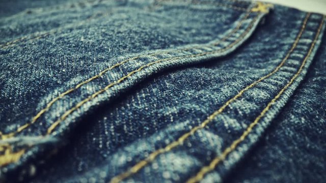 Extreme detailed of blue denim jeans cloth texture in macro dolly shot over the cloth surface. Flow view of clothing material. Textile abstract background. Vintage fashion apparel industry concept.