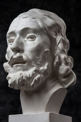 Gypsum copy of ancient statue John the Baptist head on dark textured background. Plaster sculpture...