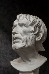 Fototapeta na wymiar Gypsum copy of ancient statue Seneca head on dark textured background. Plaster sculpture man face.
