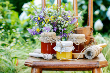 Jars with honey and bouquet of wild flowers in the garden.