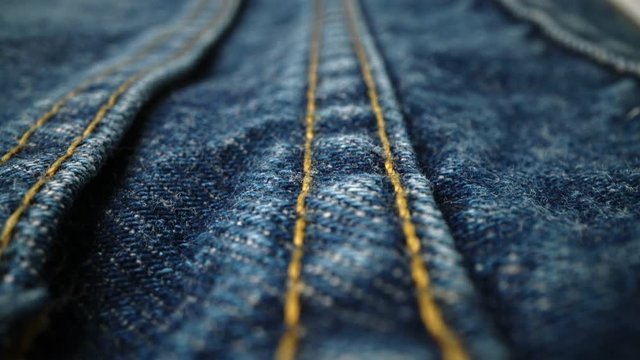 Extreme detailed of blue denim jeans cloth texture in macro dolly shot over the cloth surface. Flow view of clothing material. Textile abstract background. Vintage fashion apparel industry concept.