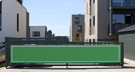 Large green advertising banner set on a wooden fence in a new residential area of mass development