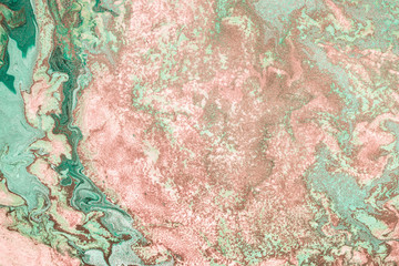 Pink gold grains are randomly scattered on Free flowing paint. Pastel background or texture in mint and pink colors