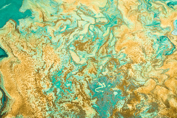 Fototapeta na wymiar Golden grains are randomly scattered on Free flowing paint. Background or texture in green and yellow colors