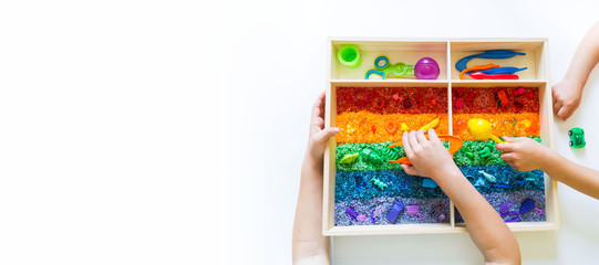 Sensory box with rainbow rice inside. Montessori material baby Copy Space - obrazy, fototapety, plakaty