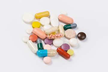 Assorted pharmaceutical medicine pills, tablets and capsules.Heap of assorted various medicine tablets and pills different colors on white background. Top view.Copy space
