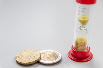 Euro-M&uuml;nzen mit Sanduhr zeigt klar: Zeit ist Geld und die Zeit l&auml;uft mit dem Geld f&uuml;r 2 EURO und 1 Euro gleicherma&szlig;en schnelllebige und kostbare Zeit