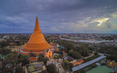 Aerial view evening of Phra Pathom Chedi, the biggest pagoda of Thailand around with many building, green trees with cloudy sky background, Nakhon Pathom Province, Thailand.