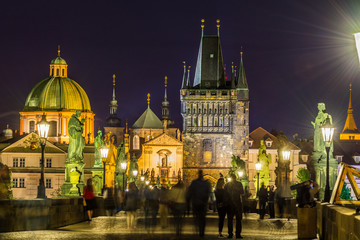 Fototapeta premium Night view of Old Town Bridge Tower and background of Church of St Francis Seraph at the bank of River Vltava, view from the Charles bridge.