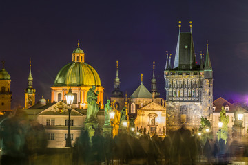 Fototapeta na wymiar Night view of Old Town Bridge Tower and background of Church of St Francis Seraph at the bank of River Vltava, view from the Charles bridge.
