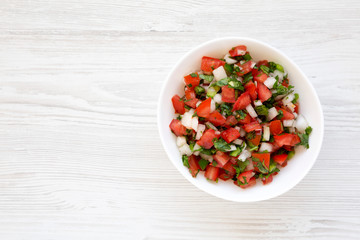 Fototapeta na wymiar Pico de Gallo in a white bowl on a white wooden surface, top view. Overhead, from above, flat lay. Space for text.