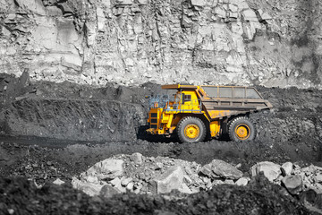 Fototapeta na wymiar Big yellow mining truck laden anthracite moves open pit coal mine