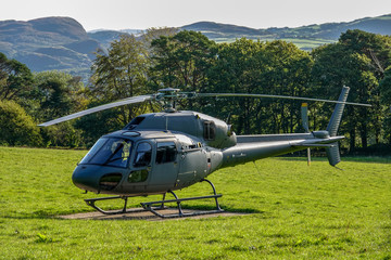 Stationary helicopter on landing pad, in the middle of a field, North Wales.