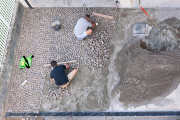Treviglio - Italy 06 October 2019, due operai specializzati posano cubetti di pietra per formare un pavimento decorativo