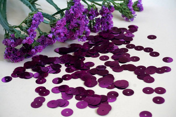 Detail of purple round sequins and purple dried flowers.