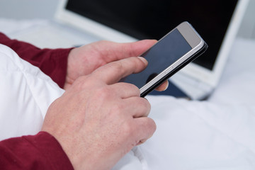 man lying in bed using mobile phone